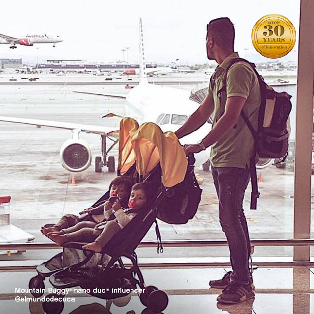 papá con dos niños pequeños en nano duo  silla de paseo, esperando en el aeropuerto - Mountain Buggy nano  duo™  influencer @elmundodecuca