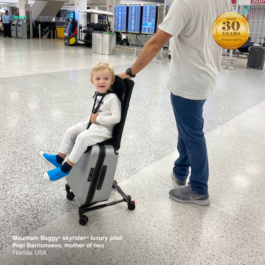 toddler at the airport riding on our skyrider ride on suitcase - Mountain Buggy skyrider luxury pilot Popi Barrionuevo, mother of two, Florida, USA
